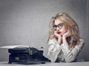 Woman looks at her type writer in frustration.